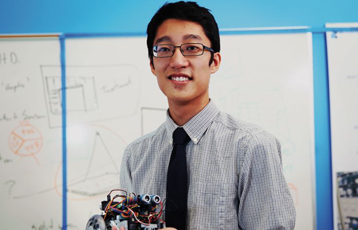 Man with Robot Male student with robot in Hand in front of Whiteboard